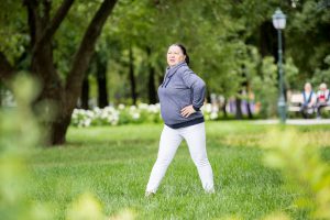 Senior woman doing exercises in green beautiful park. Healthy lifestyle