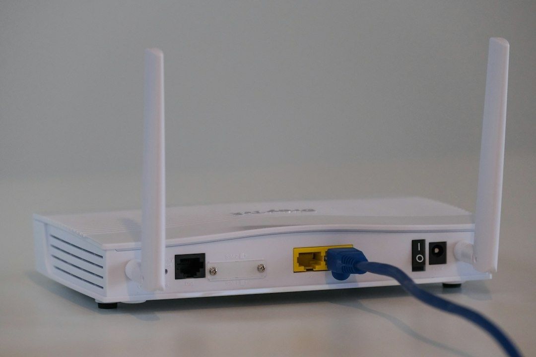 Valkoinen Wi‑Fi-reititin, antennit ja sininen verkkokaapeli